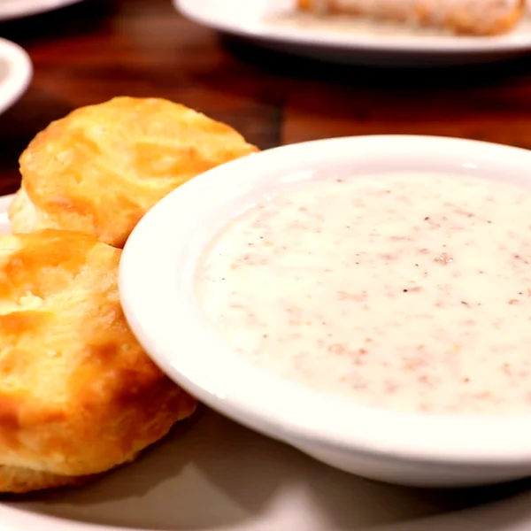 Golden homemade biscuits beside a bowl of peppered sausage gravy