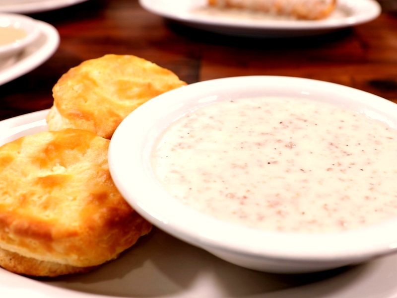 Golden homemade biscuits beside a bowl of peppered sausage gravy